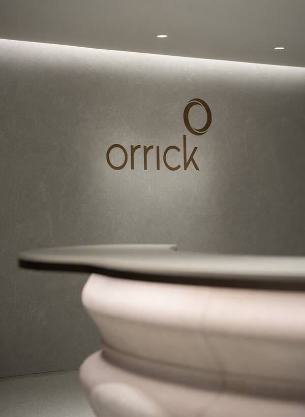 Law firm reception desk against a burnished Venetian plaster wall carrying the Orrick mark