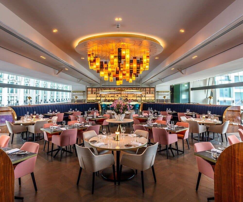 Restaurant dining room with a sculptural amber chandelier under a seamless acoustic plaster ceiling