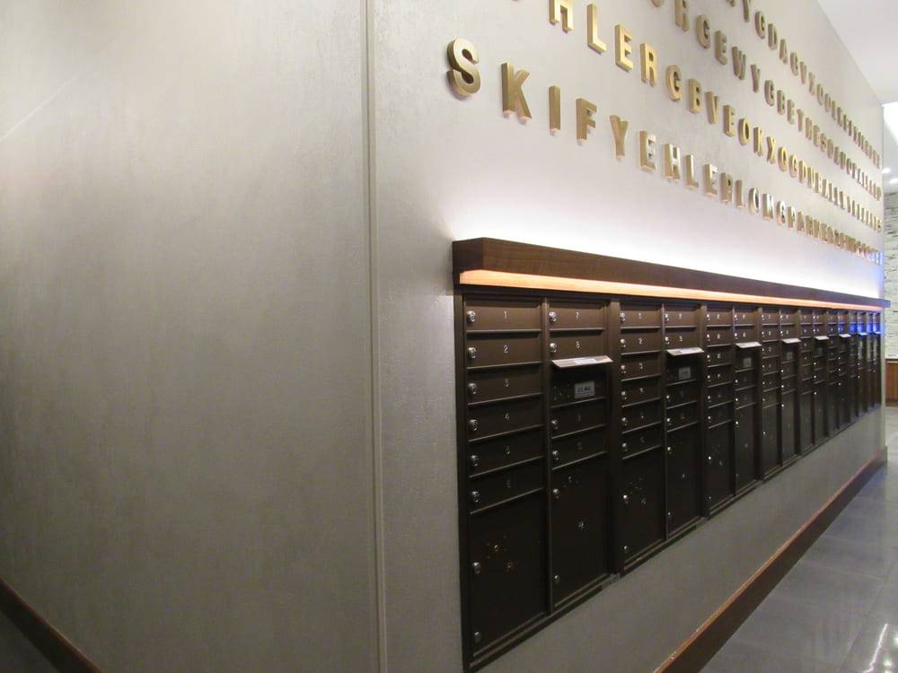 Residential mail room with a plaster-finished wall carrying the building name