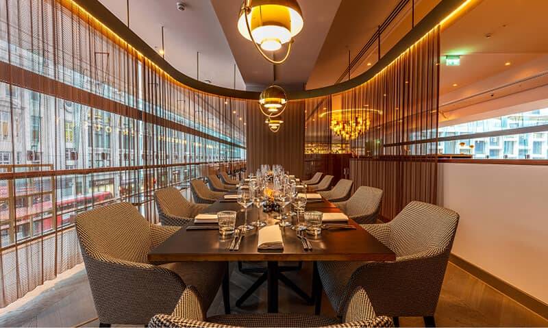 Restaurant dining room with a curved acoustic plaster ceiling and pendant lighting