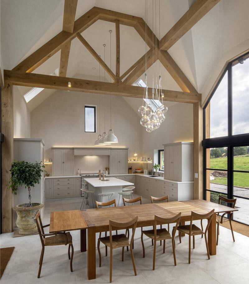 Barn conversion kitchen under an exposed oak truss ceiling finished in clay lime plaster