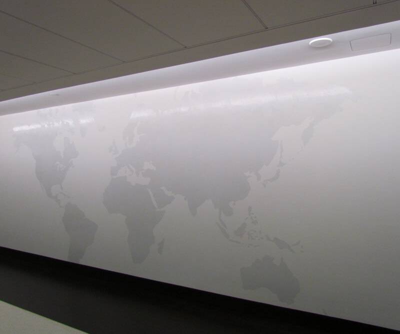 Illuminated world map etched into a striated decorative plaster wall