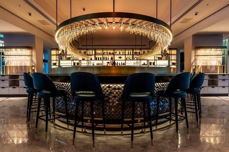 Circular bar with a suspended glass rack and dark velvet stools