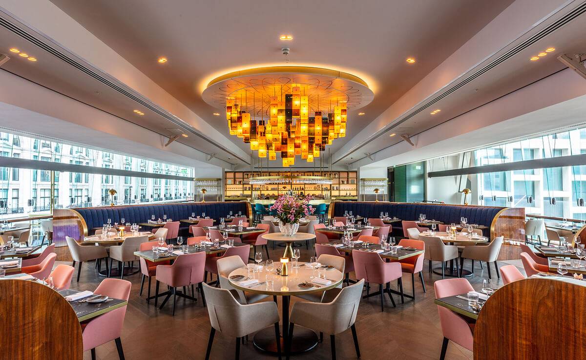 Restaurant dining room with a sculptural amber chandelier under a seamless acoustic plaster ceiling