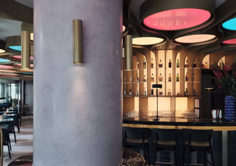Bar column wrapped in polished plaster beside a lit back bar